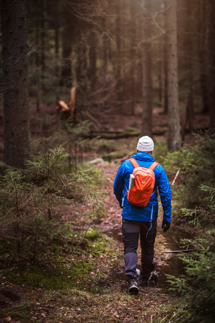 Panu Könönen kävelee kostealla metsäpolulla reppu selässään.